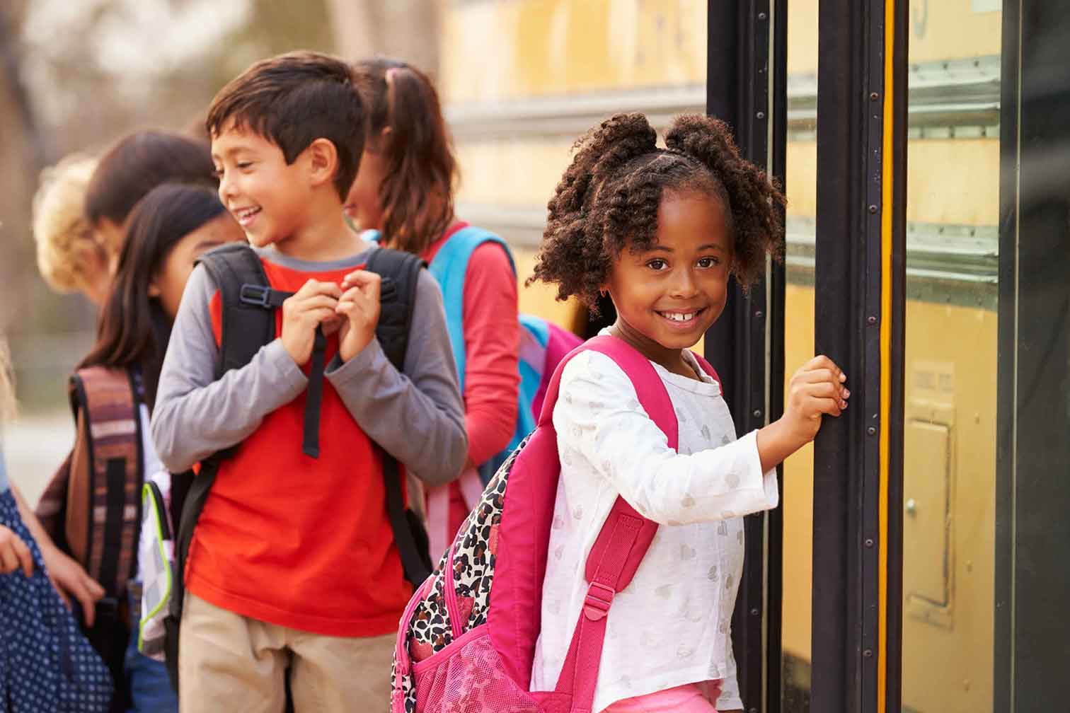 Girl smiling as she boards a school bus