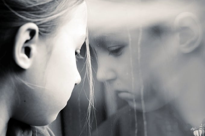 Young sad girl crying against window