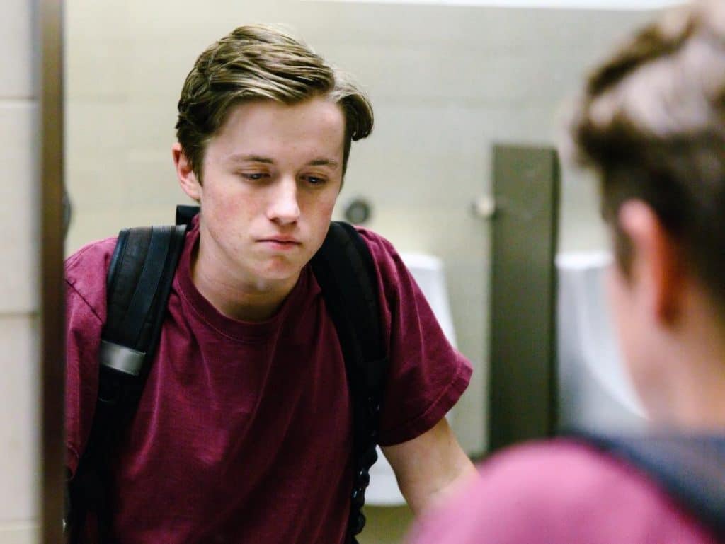 Depressed student looking in mirror, suicide awareness