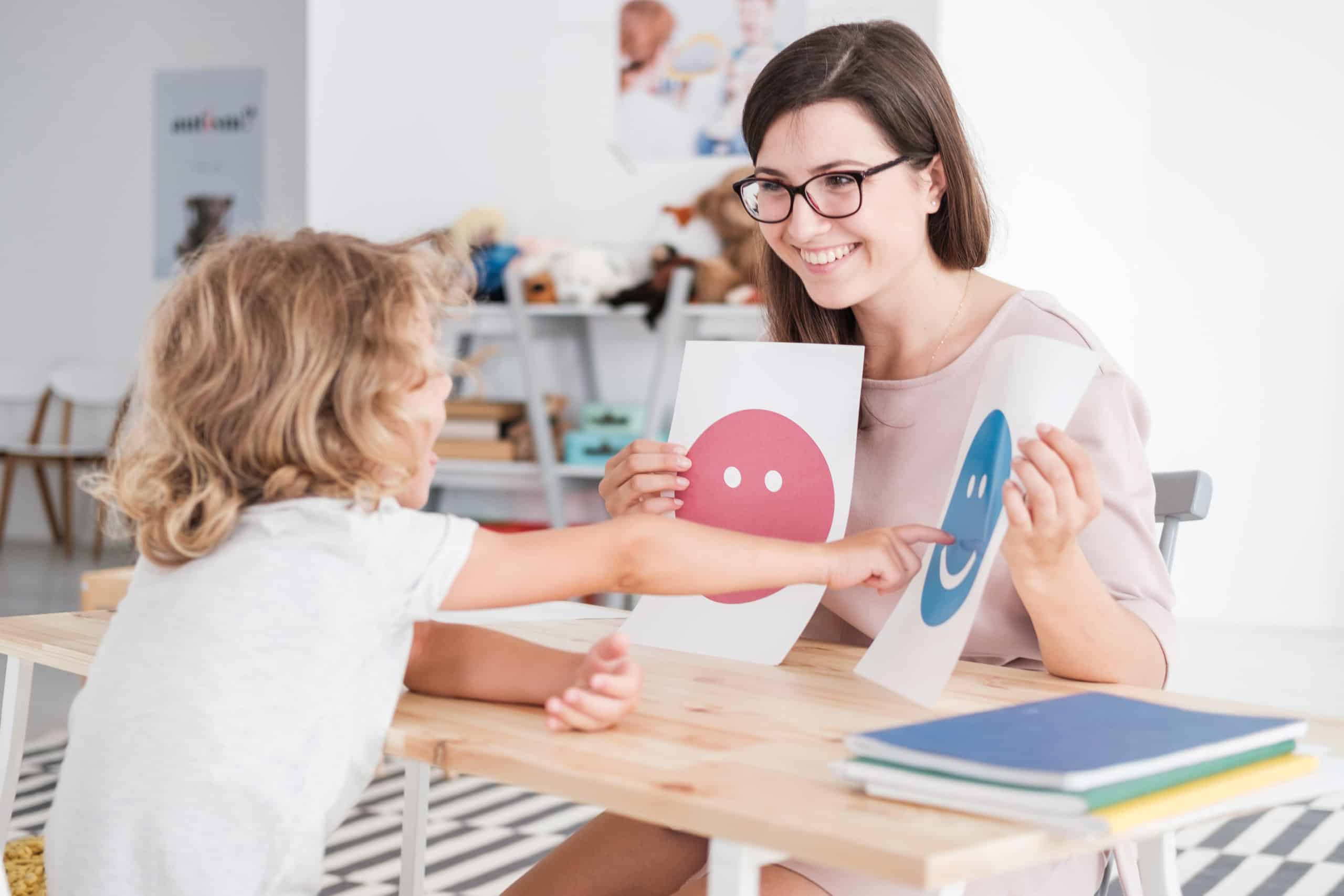 Smiling counselor holding pictures during meeting with young pat